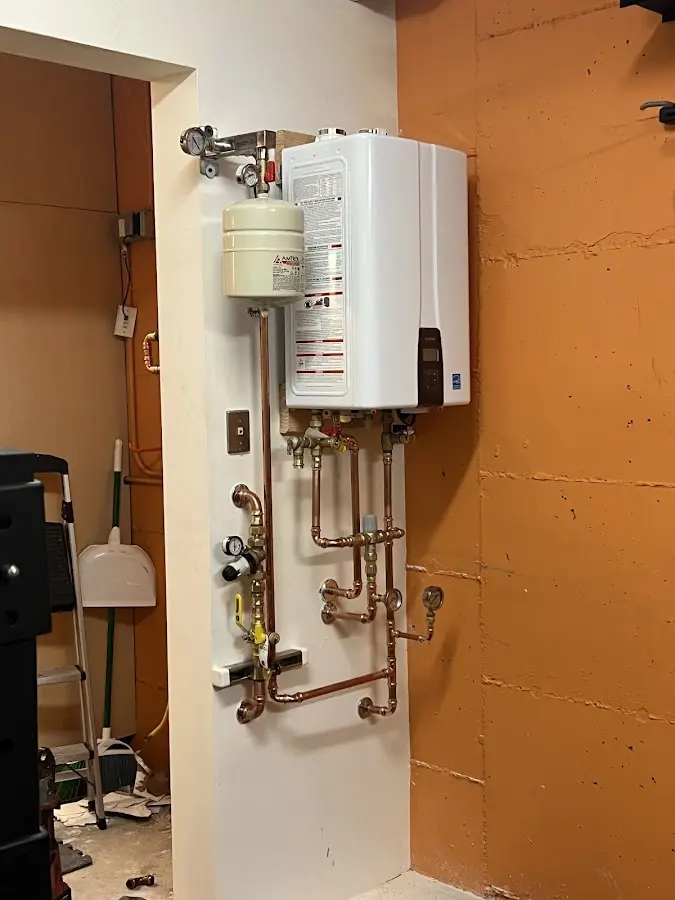 Plumbing technician inspecting water heater connections in Winterset